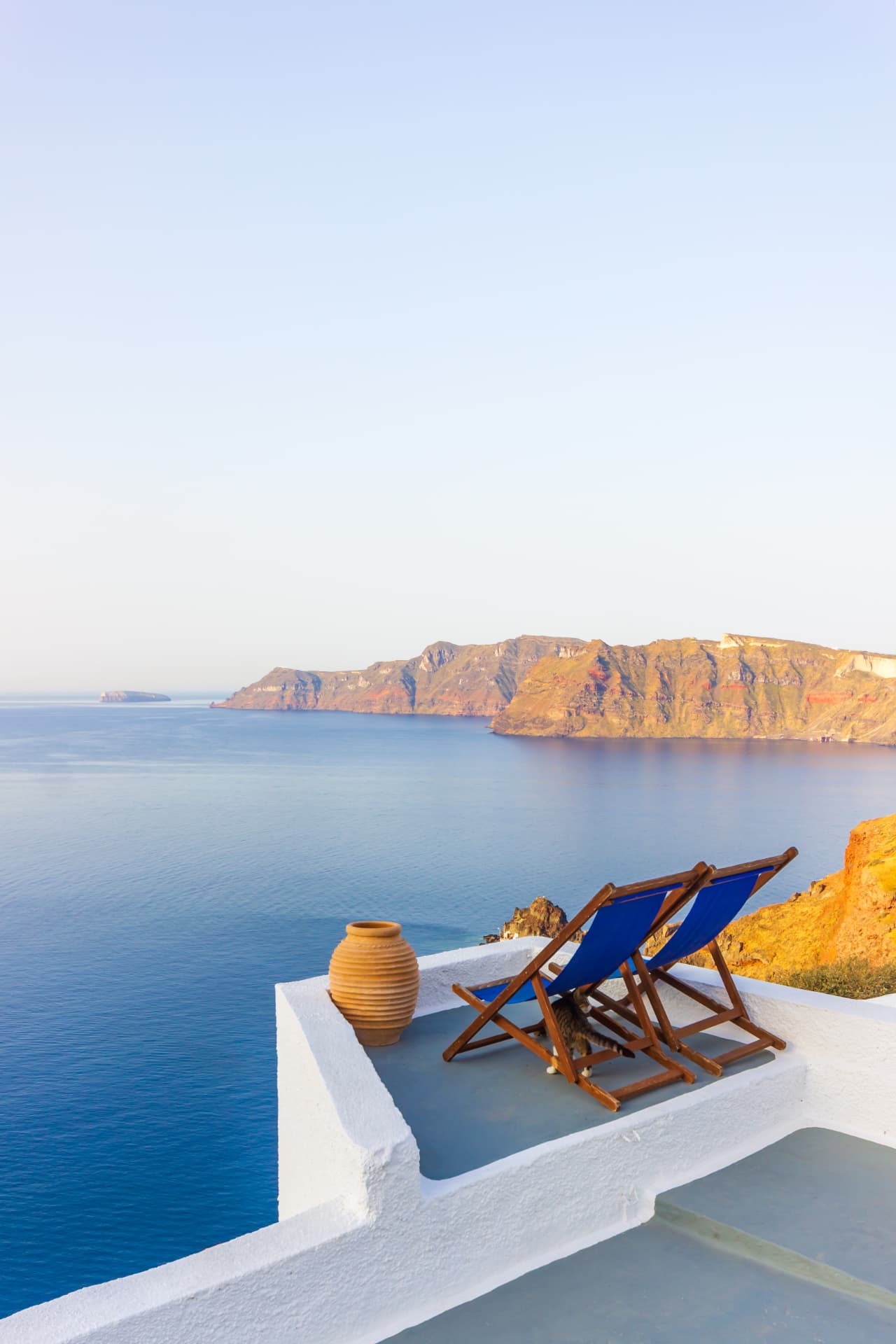 Two deckchairs on a white terrace overlooking the blue sea